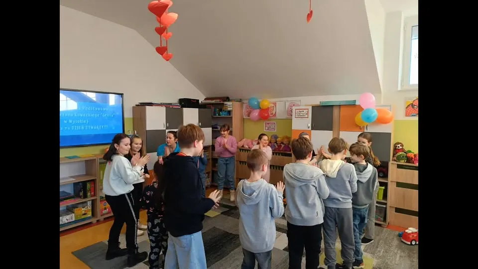 Dzieci bawią się w kolorowej sali oddziału przedszkolnego udekorowanej balonami i papierowymi sercami