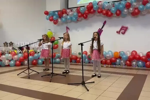 Trzy uczennice z oddziału przedszkolnego śpiewają na scenie