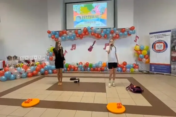 Dwie uczennice śpiewają na scenie udekorowanej balonami