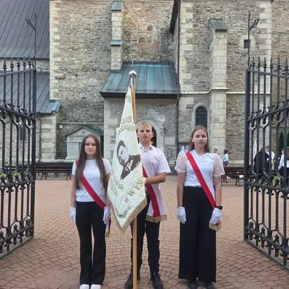 Poczet sztandarowy szkoły przed bramą kościoła w Wysokiej
